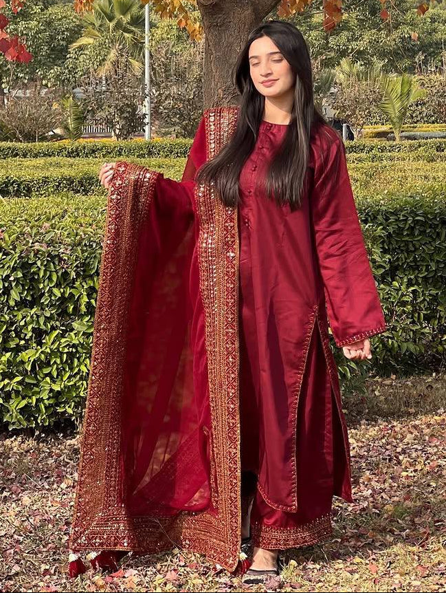 Woman in a red traditional outfit standing under a tree with autumn leaves