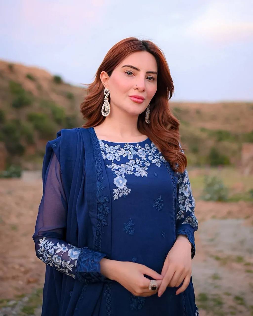 "Elegant Woman in Blue Embroidered Dress Amidst Natural Scenery"
