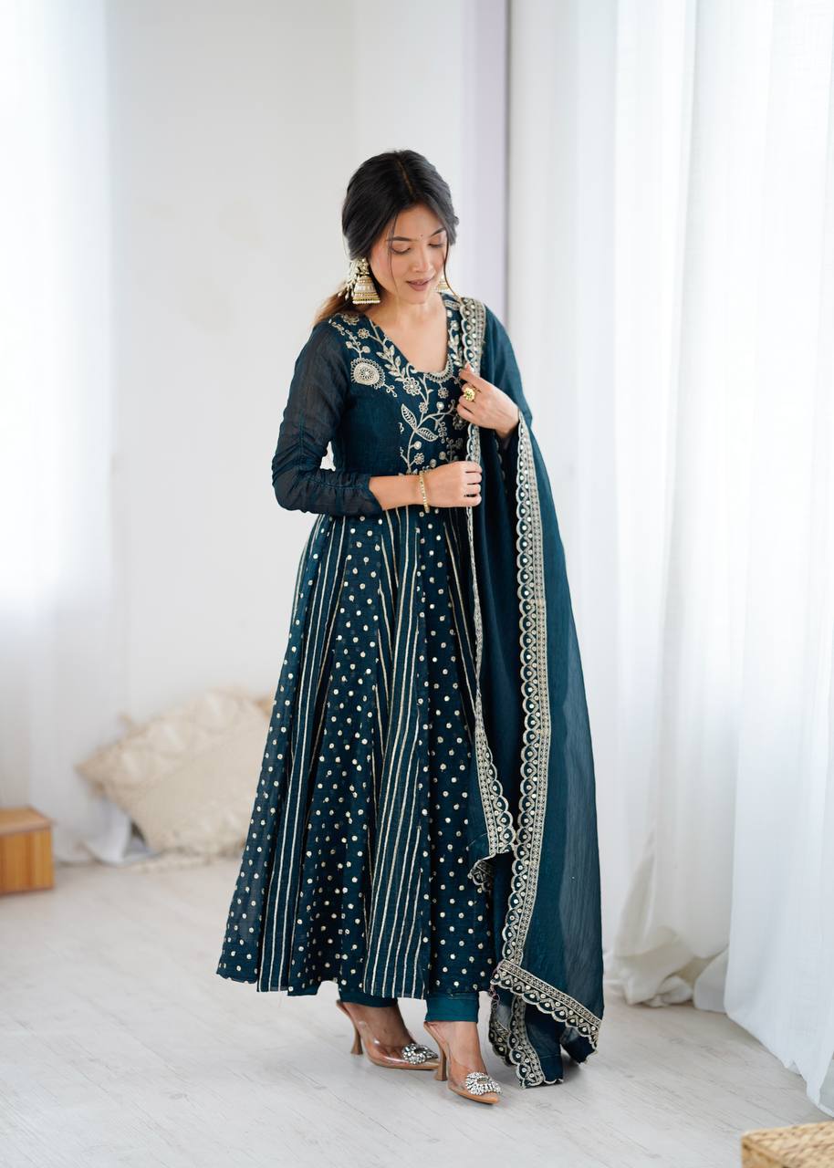 Woman wearing a traditional outfit with a dark green dupatta in a bright room.