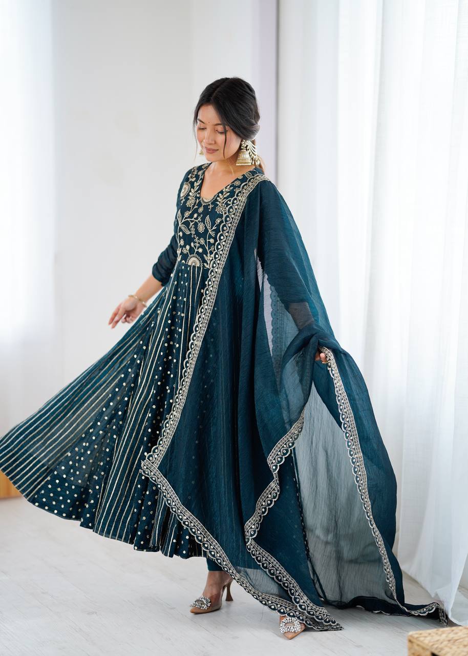 Woman wearing a long, dark blue embroidered dress with a white background